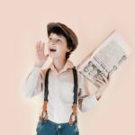 cheerful boy holding aged newspaper against beige background