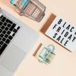 top view of silver macbook beside a shopping cart and black friday sale signage